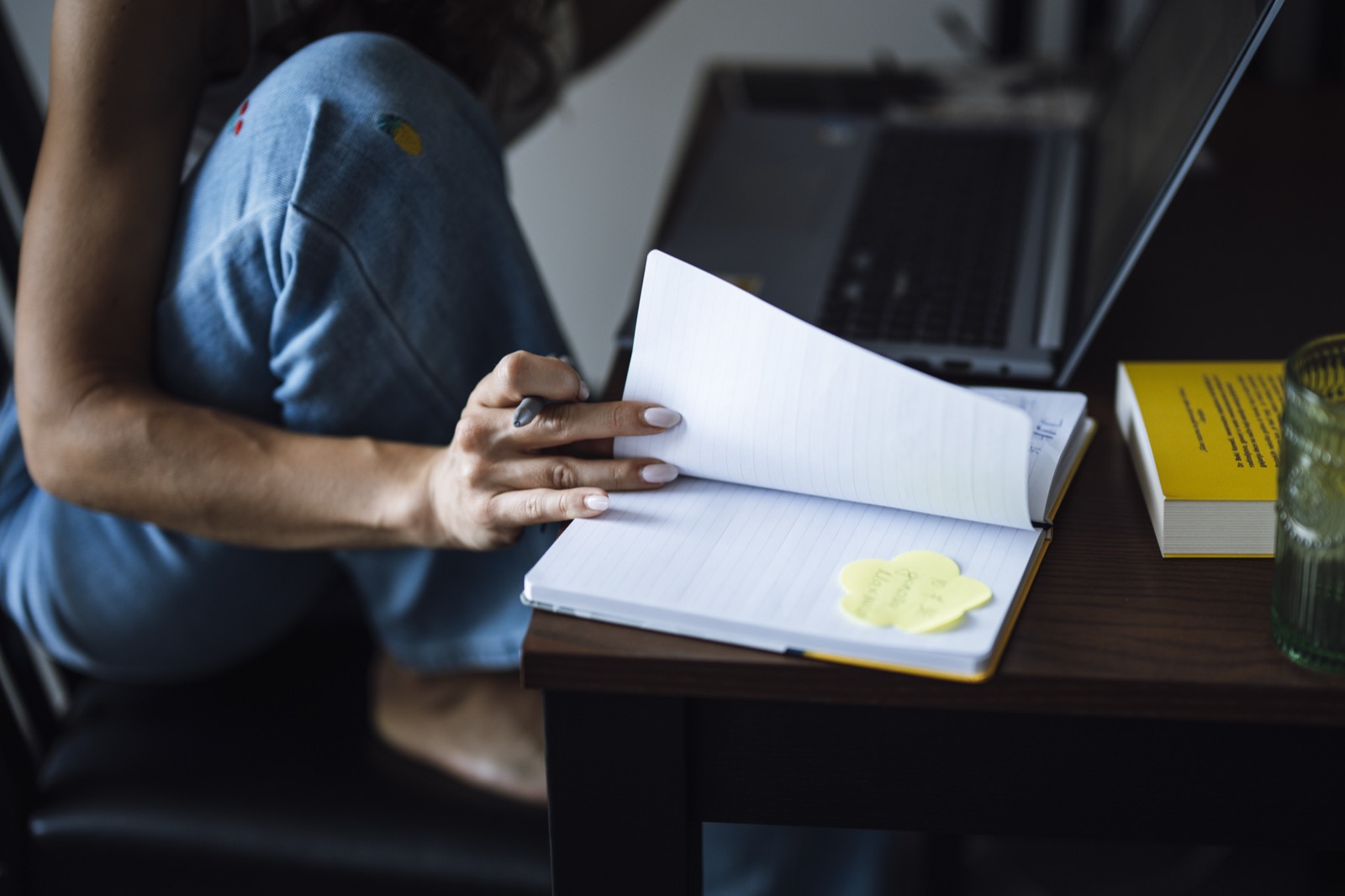 A person sitting at a table with an open notebook and a laptop