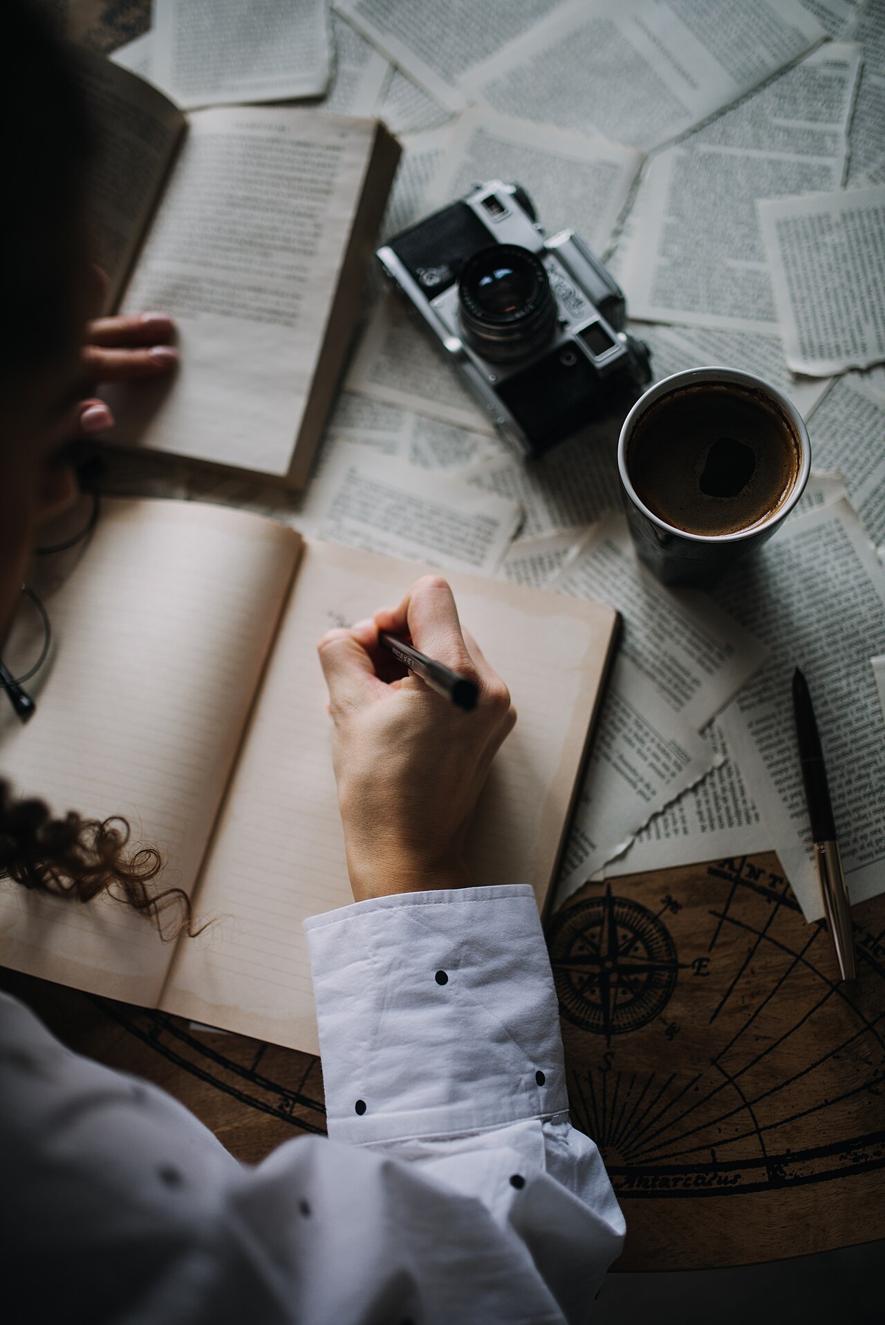 A person writing in an open notebook at a table