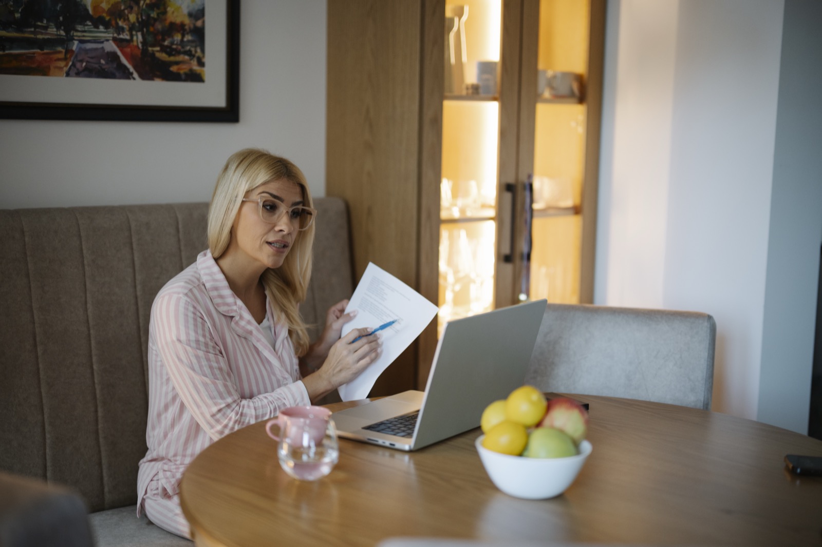 A woman seated at a table looking through paper documents
