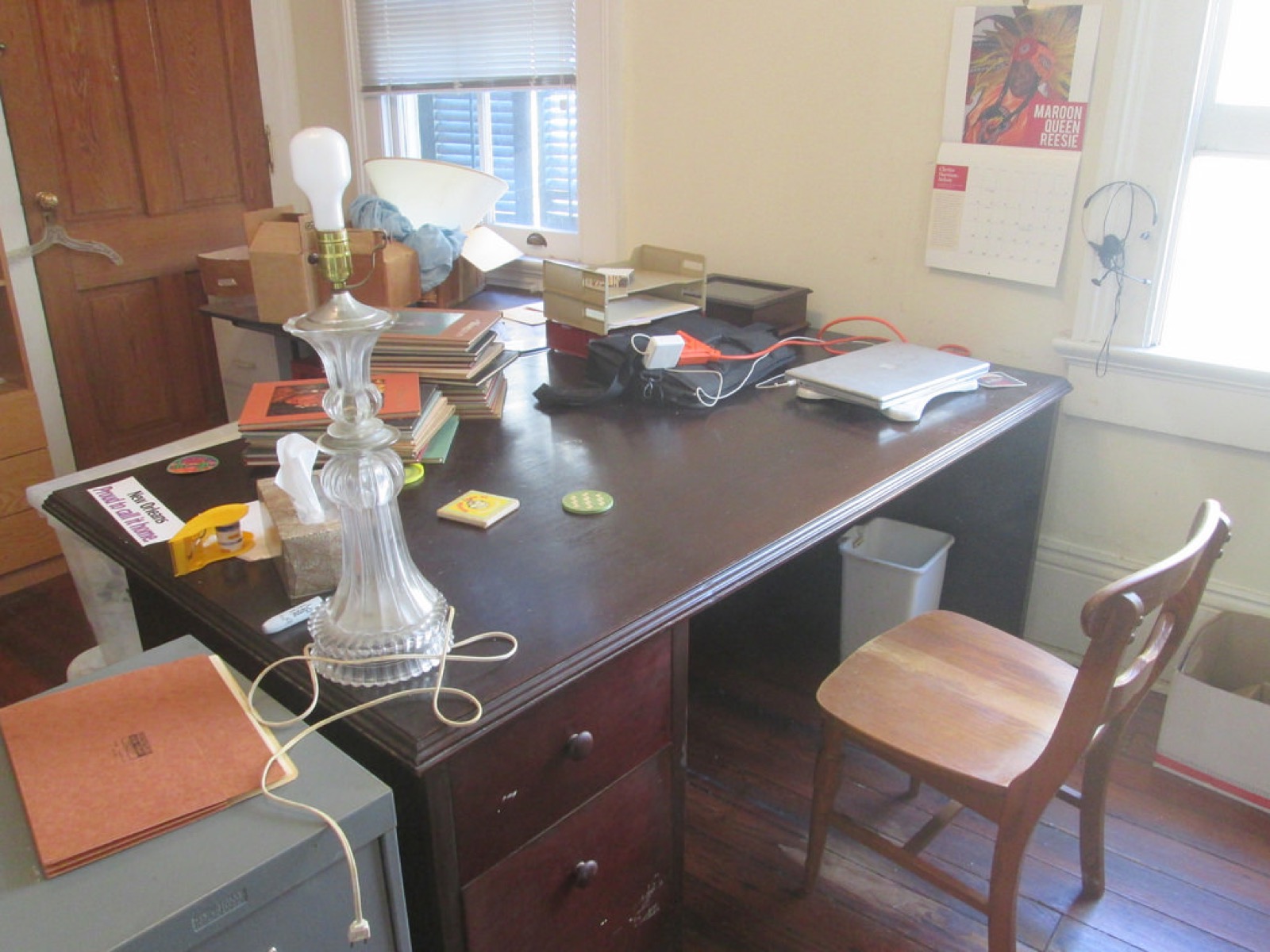 A home office desk in New Orleans with paper trays, notebooks, a laptop, and a chair