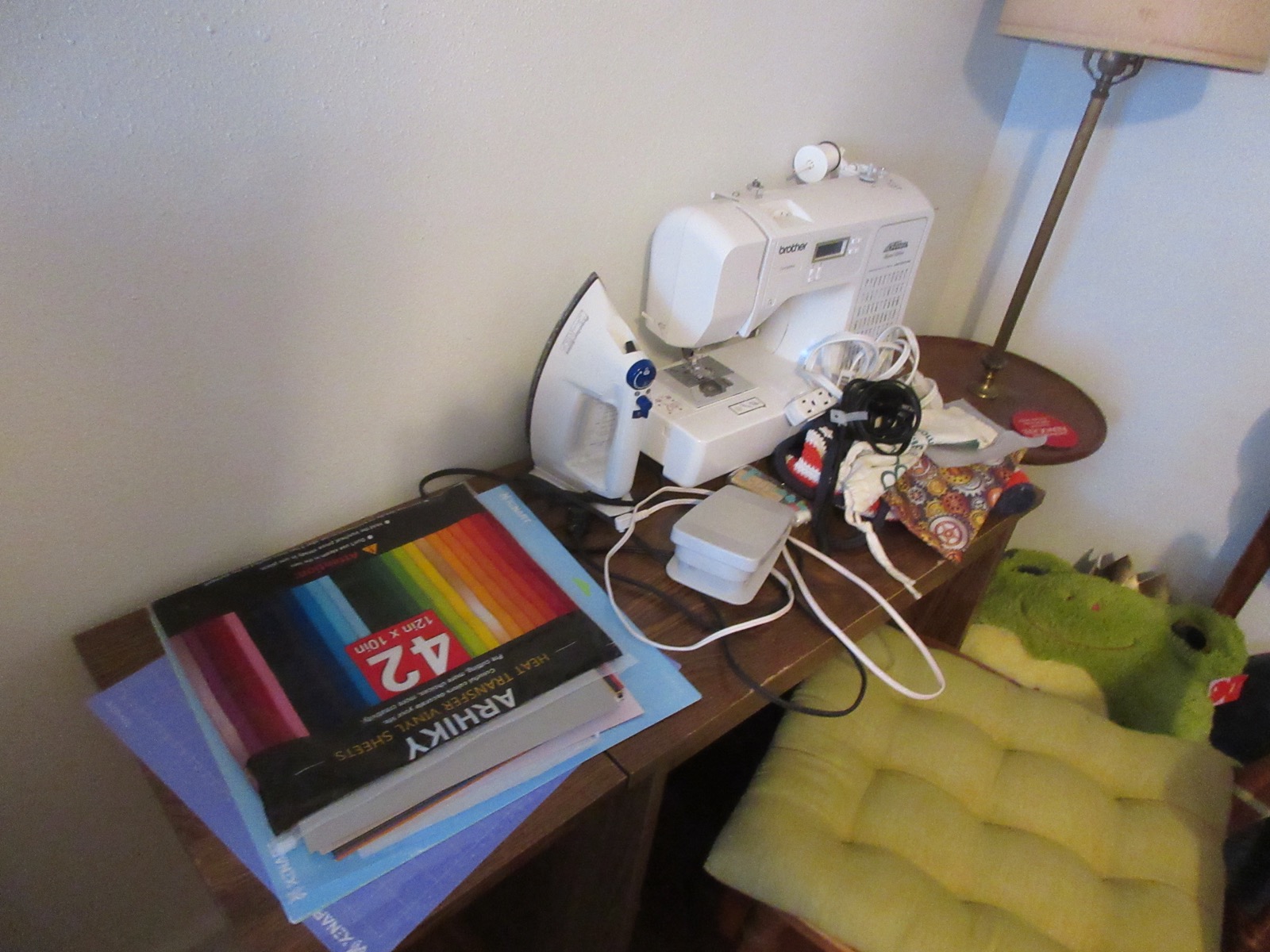 A home sewing table with a Brother sewing machine, fabric, and nearby project supplies